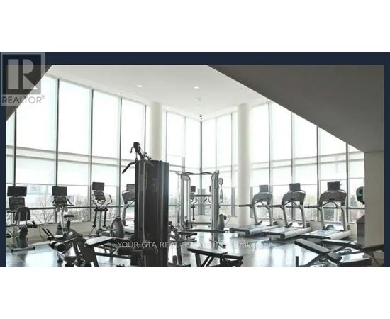 A gym with a row of treadmills and a row of stationary bikes.