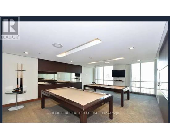 A billiard table is in the middle of a room with a pool table and a TV.