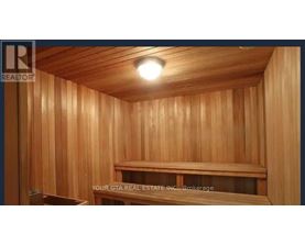 A wooden sauna room with a bench and a light on the ceiling.