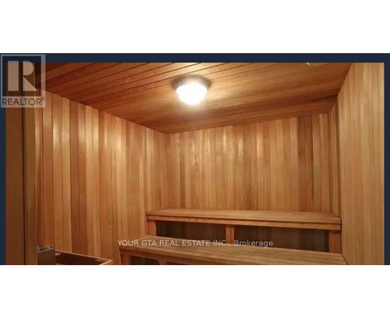 A wooden sauna room with a bench and a light on the ceiling.