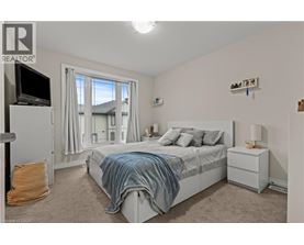 A bedroom with a bed, nightstand, and window with curtains.