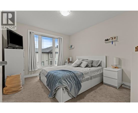 A bedroom with a bed, nightstand, and window with curtains.