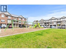 A playground with a swing set and a green lawn in front of apartment buildings.