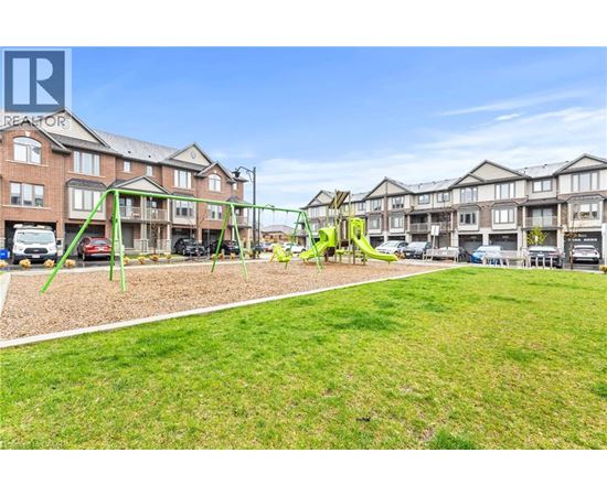 A playground with a swing set and a green lawn in front of apartment buildings.