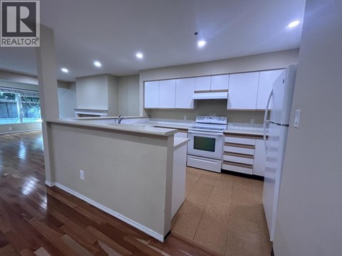 A kitchen with white cabinets and a wooden floor.