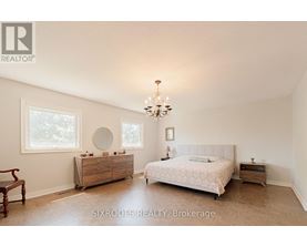 A bedroom with a large bed, a dresser, and a chandelier.