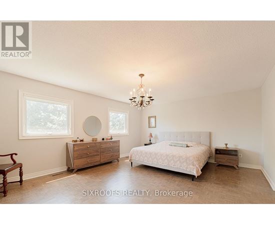 A bedroom with a large bed, a dresser, and a chandelier.