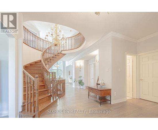 A large open space with a spiral staircase and a table with a vase of flowers on it.