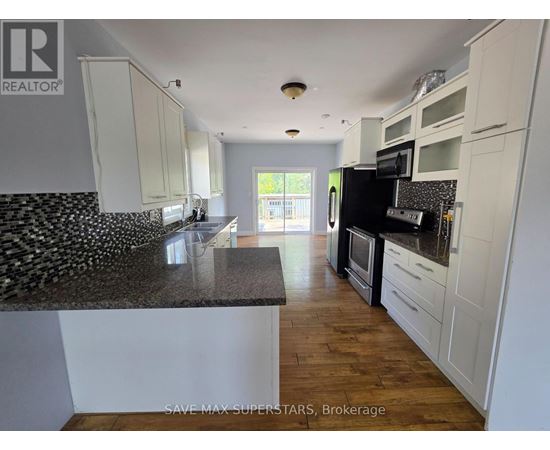 A kitchen with white cabinets and a black and white tiled backsplash.