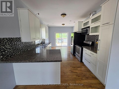 A kitchen with white cabinets and a black and white tiled backsplash.