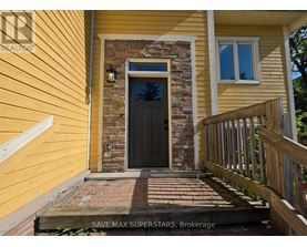 A yellow house with a black door and a stone pillar.