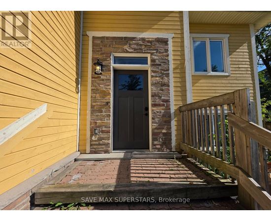 A yellow house with a black door and a stone pillar.