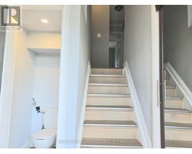 A staircase in a house with a toilet in the foreground.