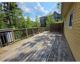 A wooden deck with a railing and a building in the background.