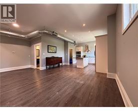 A spacious room with wood flooring and a large window.