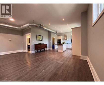 A spacious room with wood flooring and a large window.