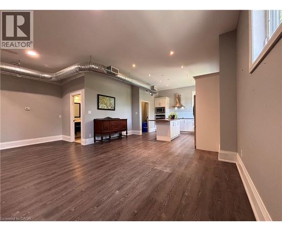 A spacious room with wood flooring and a large window.