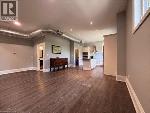 A spacious room with wood flooring and a large window.
