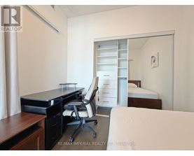 A bedroom with a desk and a bed in the background.