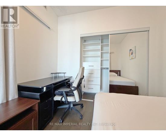 A bedroom with a desk and a bed in the background.