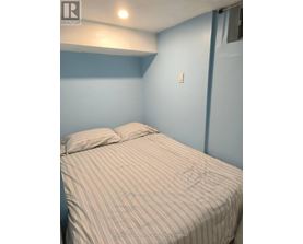 A bed with a striped comforter is in a room with blue walls.
