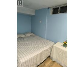 A bedroom with a bed and a small table with a vase of flowers on it.