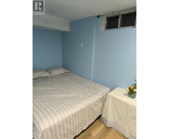 A bedroom with a bed and a small table with a vase of flowers on it.