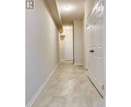 A hallway with a white door and tiled floor.