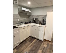 A kitchen with white cabinets and a wooden floor.