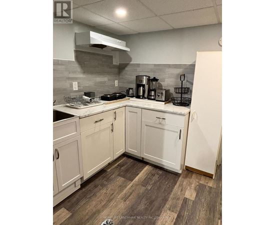 A kitchen with white cabinets and a wooden floor.