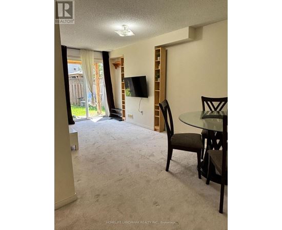 A living room with a carpeted floor and a glass table with chairs.