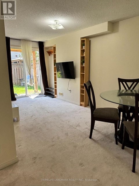 A living room with a carpeted floor and a glass table with chairs.