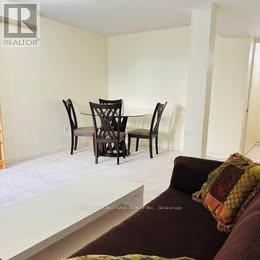 A living room with a couch, chairs and a dining table.
