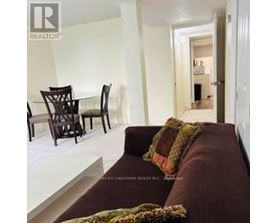 A living room with a brown couch and a glass table.