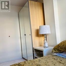 A bedroom with a bed, a nightstand with a lamp, and a wardrobe.