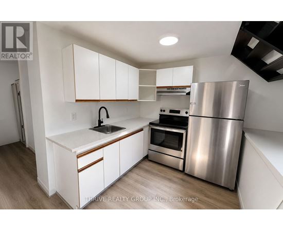 A kitchen with white cabinets and a stainless steel refrigerator.