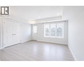 A white room with a window and a wooden floor.