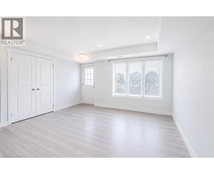 A white room with a window and a wooden floor.
