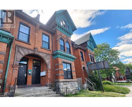 A red brick building with a green trim and a sign that says "RE/MAX ABOUT TOWN".
