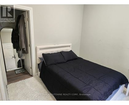 A bedroom with a bed, pillows, and a coat hanging on the door.