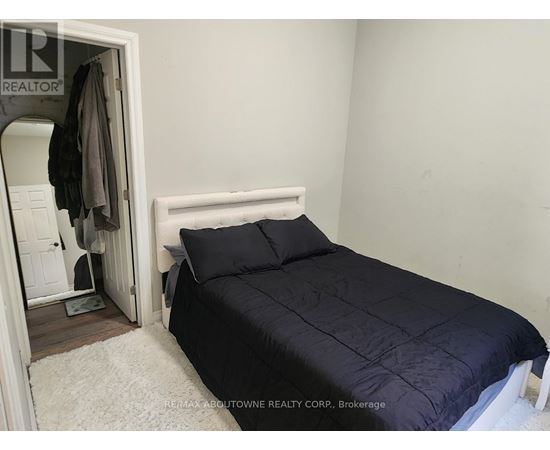 A bedroom with a bed, pillows, and a coat hanging on the door.