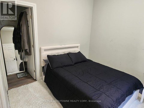 A bedroom with a bed, pillows, and a coat hanging on the door.