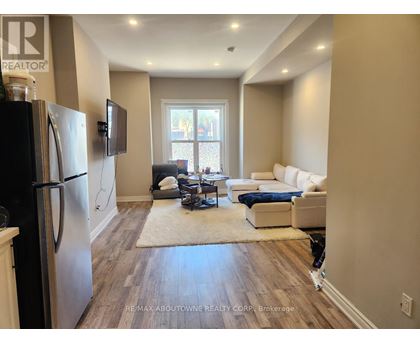 A kitchen with a refrigerator and a living room with a couch and a television.