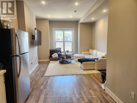 A kitchen with a refrigerator and a living room with a couch and a television.