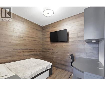 A bedroom with a bed, chair, and a television on the wall.
