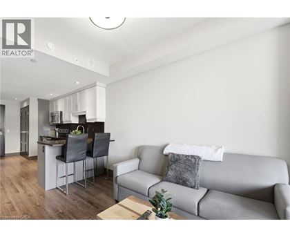 A modern living room with a grey couch and a kitchen area in the background.