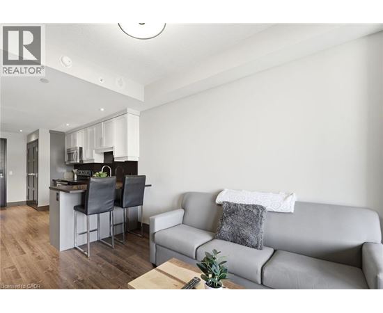 A modern living room with a grey couch and a kitchen area in the background.