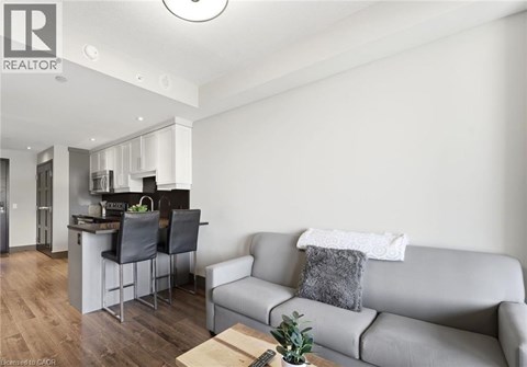 A modern living room with a grey couch and a kitchen area in the background.