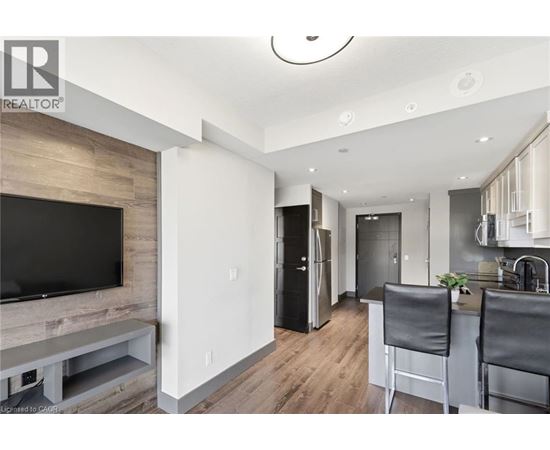 A modern kitchen with a bar stool and a television.