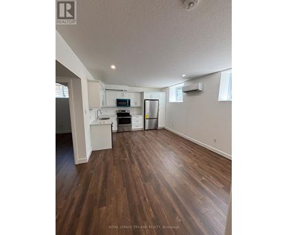 A kitchen with white cabinets and a wooden floor.